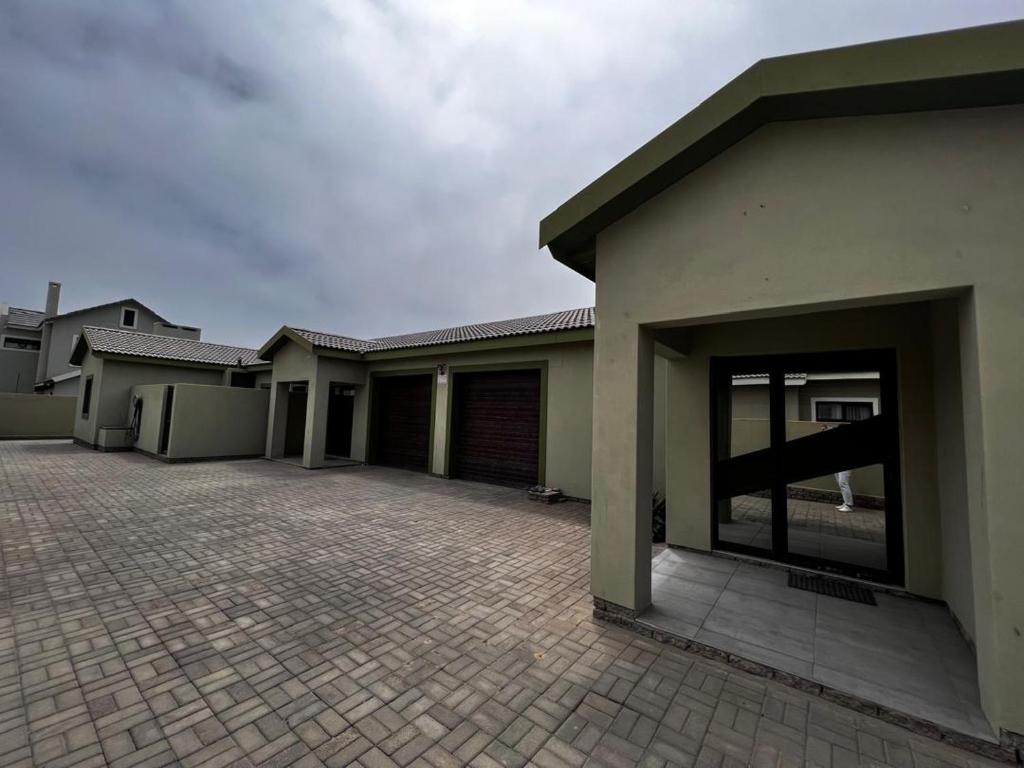 ein Haus mit einer gepflasterten Auffahrt davor in der Unterkunft Leadwood Flat in Mondesa