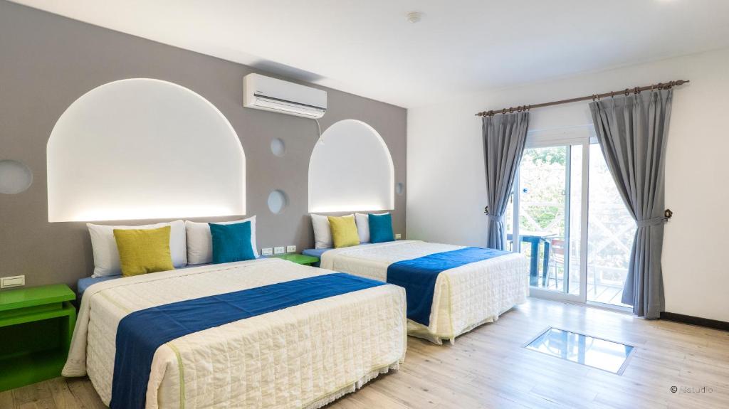 two beds in a room with arched windows at Ocean Star B&B in Kenting