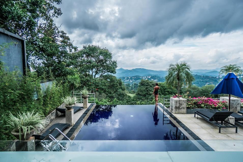 a man standing next to a swimming pool in a house at The Theva Residency in Kandy