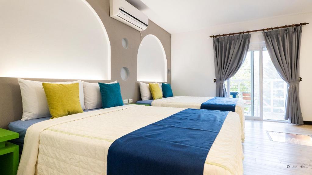 a bedroom with two beds with blue and yellow pillows at Ocean Star B&B in Kenting