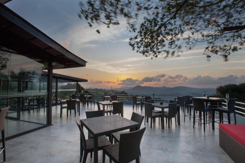 a patio with tables and chairs with a sunset in the background at The Theva Residency in Kandy