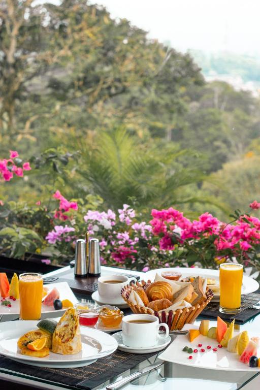 a table topped with plates of food and orange juice at The Theva Residency in Kandy