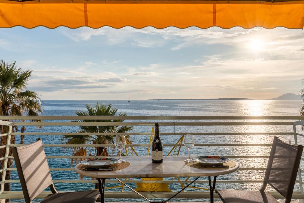 - une table avec une bouteille de vin sur un balcon donnant sur l'océan dans l'établissement Le Soleil Front de Mer Centre Juan Les Pins, à Antibes