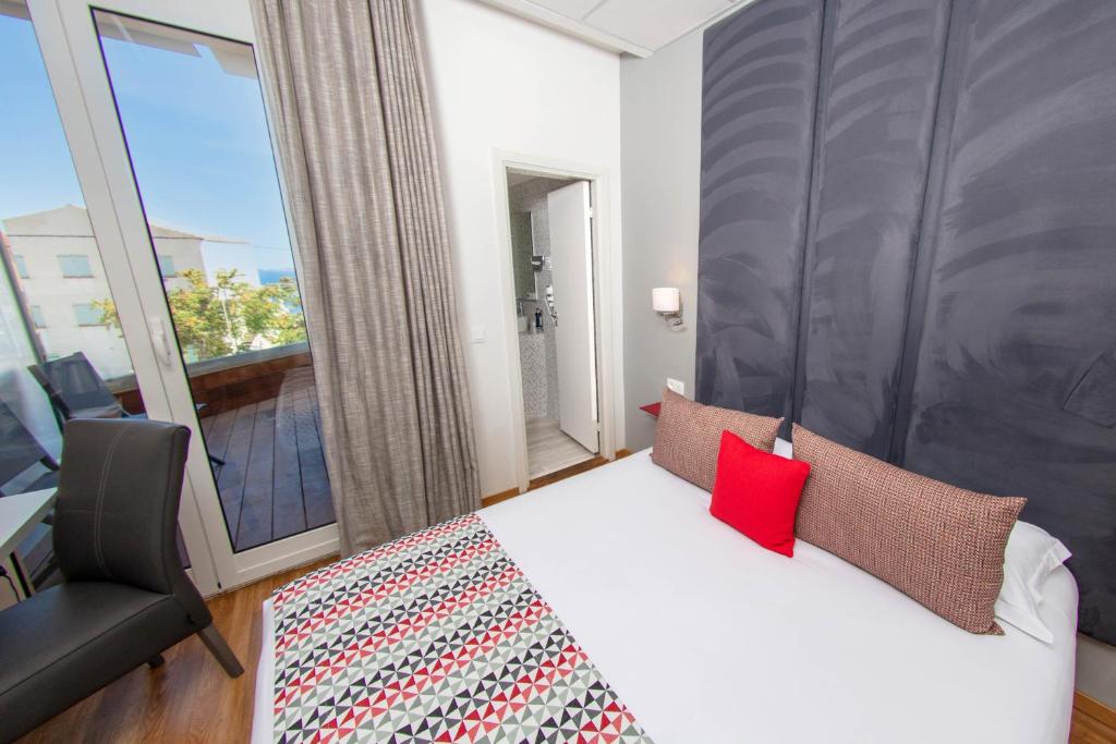 a bedroom with a bed and a large window at Hôtel Méditerranée in Calvi