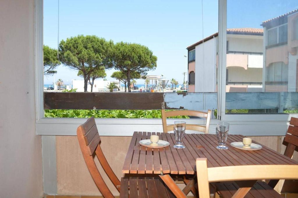 d'une table et de chaises en bois sur un balcon avec une fenêtre. dans l'établissement Appartement 2 pièces 4 couchages ST CYPRIEN PLAGE SC510-14D1, à Saint Cyprien Plage