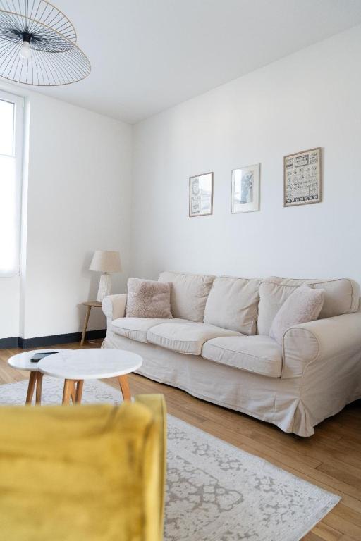 un salon blanc avec un canapé blanc et une table dans l'établissement La maison Janisse - gîte en centre-ville avec jardin, à Limoges
