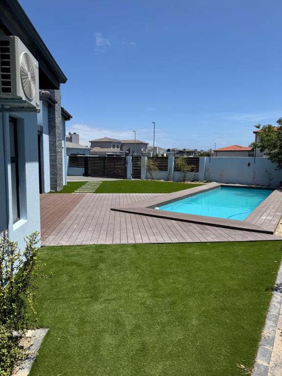 een achtertuin met een zwembad en groen gras bij Tinchley Havanna, Luxury 3 Bedroom home in Kaapstad