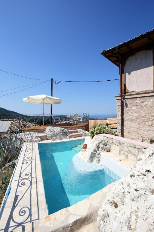 a pool with an umbrella next to a building at Gragada House in Katouna