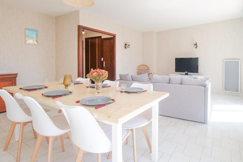 une salle à manger avec une table et des chaises blanches dans l'établissement Bel appartement 6 personnes - Quartier Arago, à Les Sables-dʼOlonne