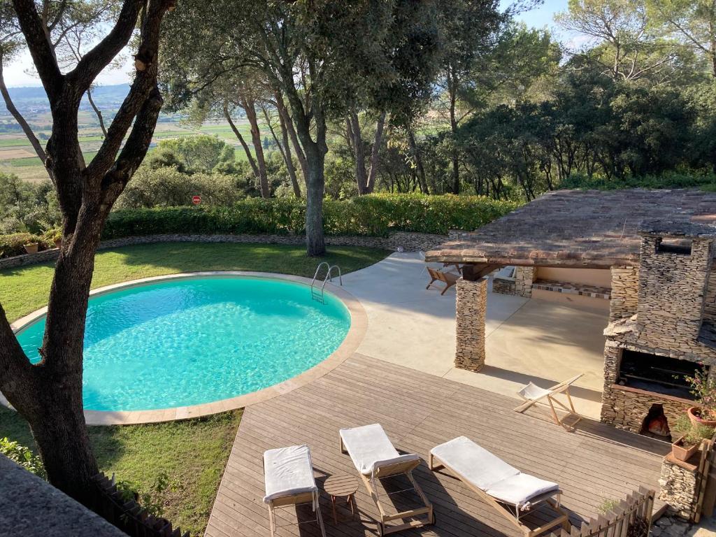 - une piscine et une terrasse avec des chaises et une cheminée dans l'établissement 757 Chemin du Vialat, à Boissières