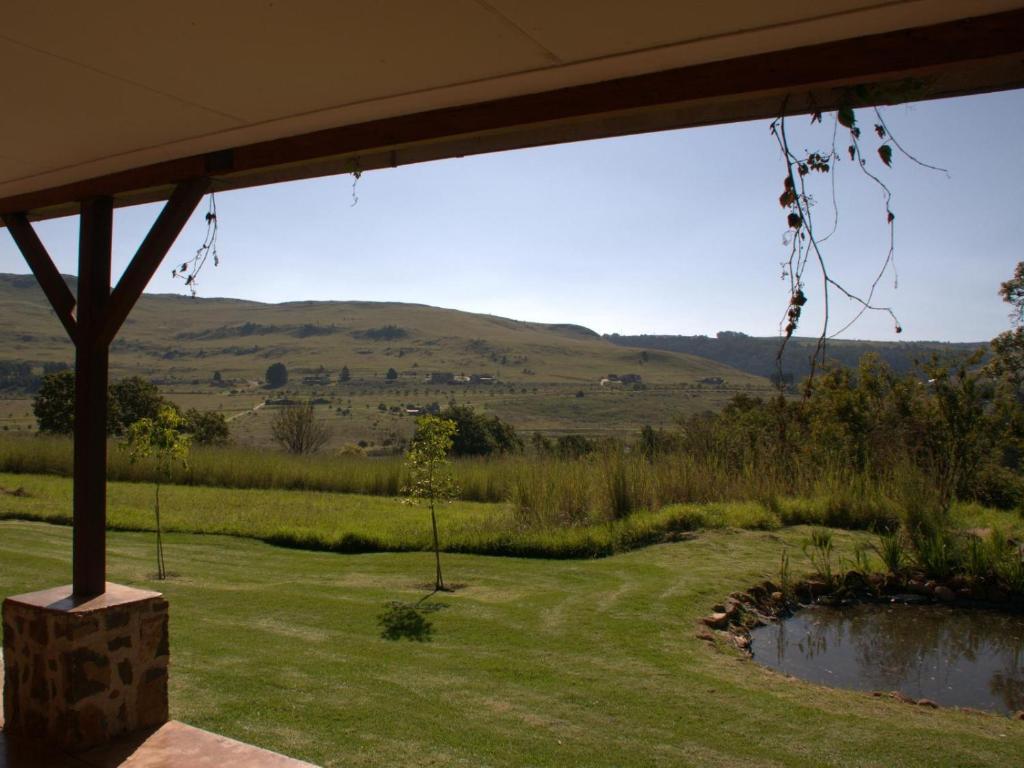 a view from the porch of a house with a pond at Watersmeet cottages in Dullstroom