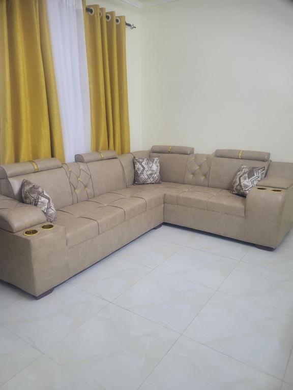 a couch in a living room with yellow curtains at Crystaljen Apartment in Mtwapa