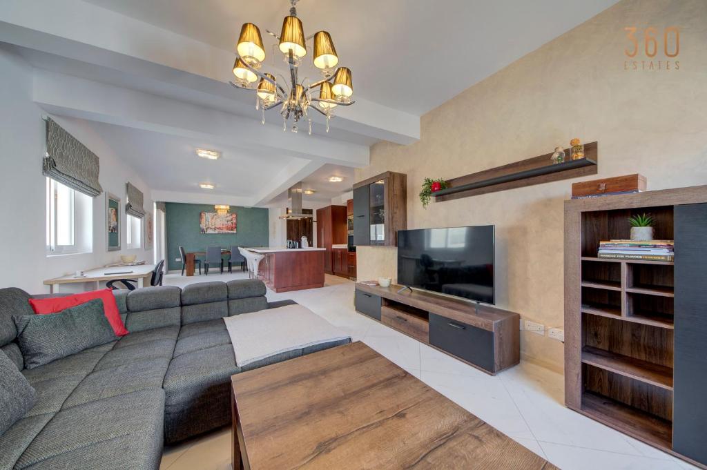 a large living room with a couch and a tv at Stunning 2BR home with spacious living in Ta'Xbiex by 360 Estates in Taʼ Xbiex