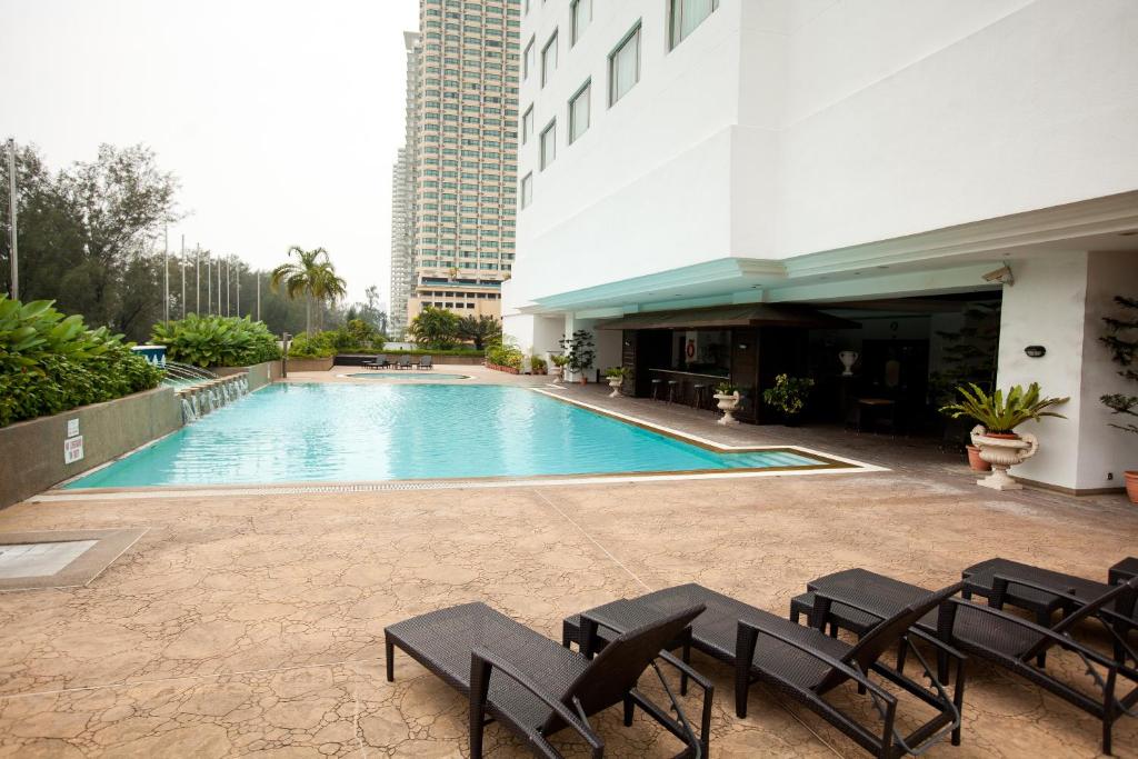 uma piscina com cadeiras e um edifício em Evergreen Laurel Hotel Penang em George Town