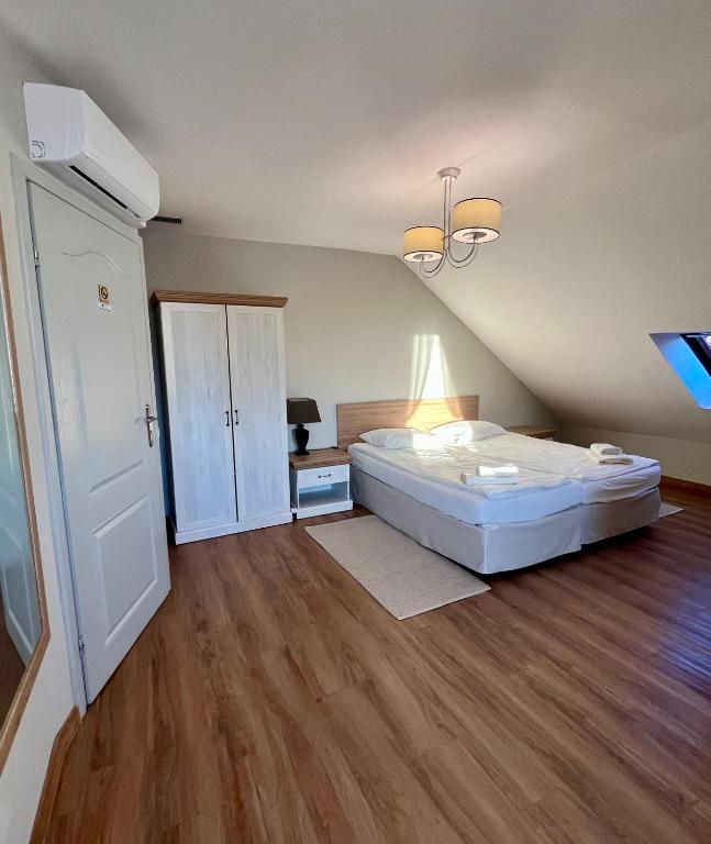 a bedroom with a large white bed and wooden floors at Hotel Nad Stawem in Bogacica