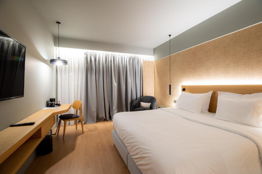 a hotel room with a large bed and a desk at Magnes Hotel in Volos