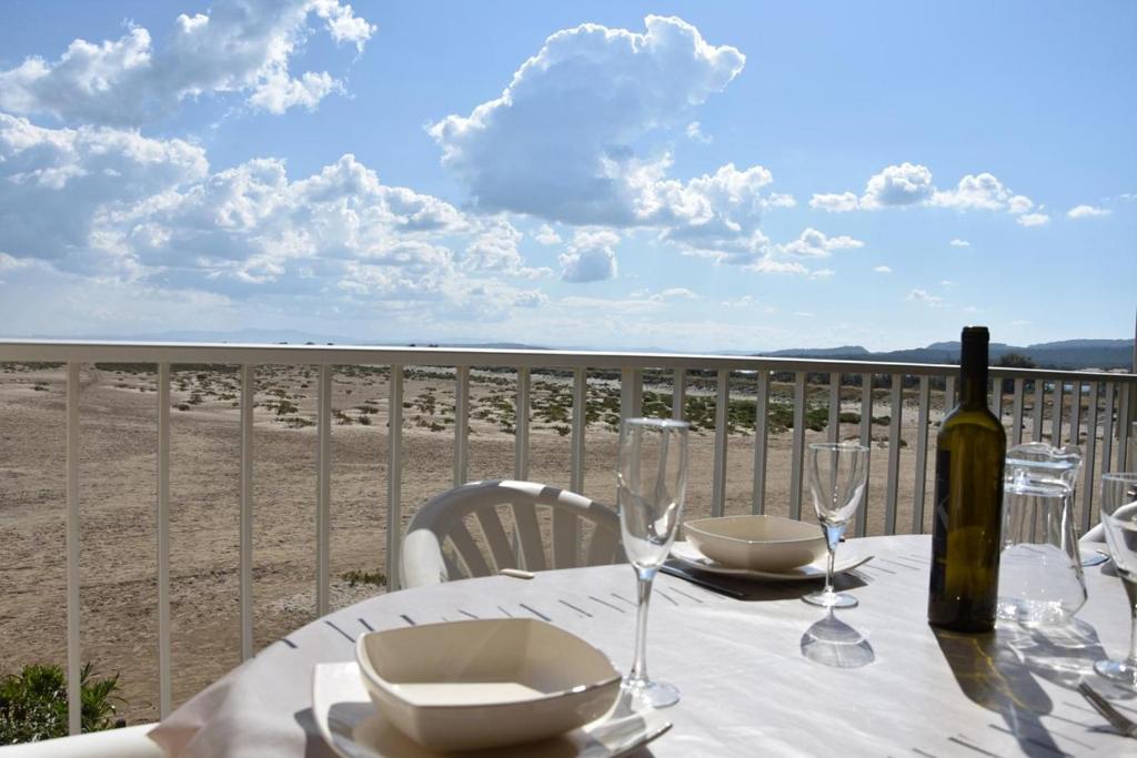 - une table avec une bouteille de vin et des verres sur la plage dans l'établissement Appartement vue mer 4 pièces - Gruissan Ayguades AY110-R06, à Narbonne-Plage