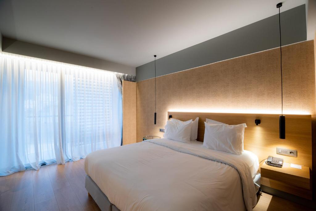 a bedroom with a large bed and a large window at Magnes Hotel in Volos