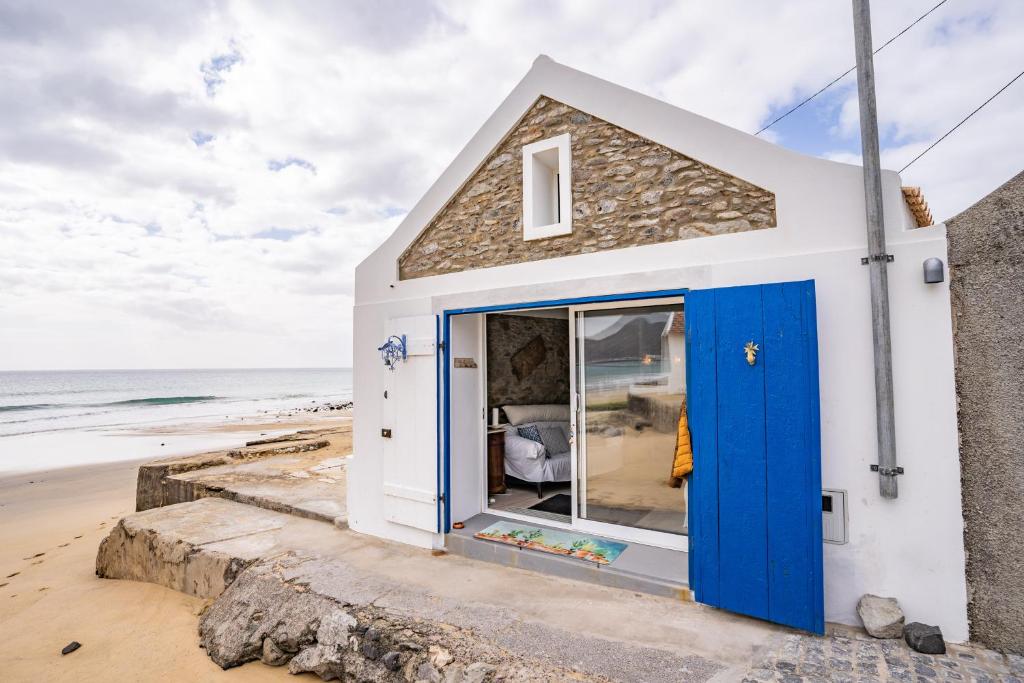 a tiny house with blue doors on the beach at Casa Neverland in Vila Baleira