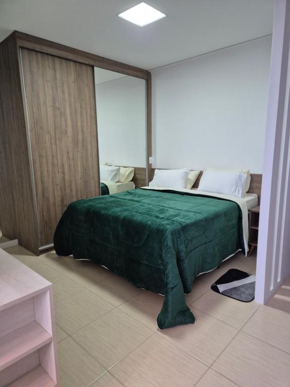 莫日-达斯克鲁济斯Loft, seu espaço com conforto的卧室里有一张床，上面铺着绿色毯子