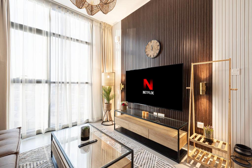 a living room with a large television and a clock at 1BR Signature Apartment in Sharjah in Sharjah