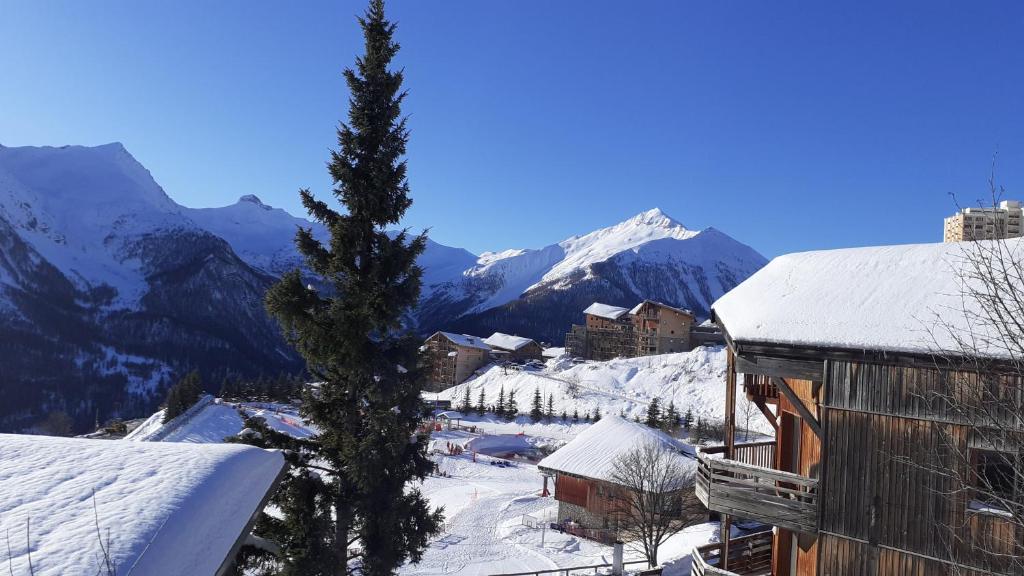 una montaña cubierta de nieve con una ciudad y un árbol en chalet à Orcieres merlette pour 10, en Orcières