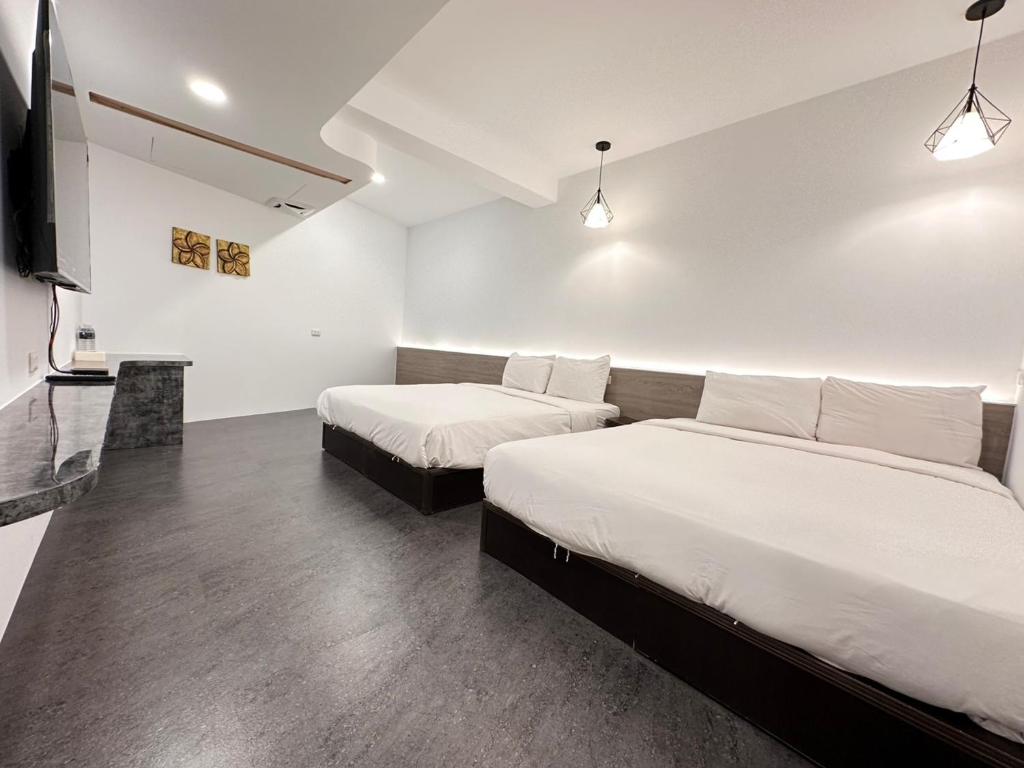a bedroom with two beds and a flat screen tv at Kenting Hostel in Kenting