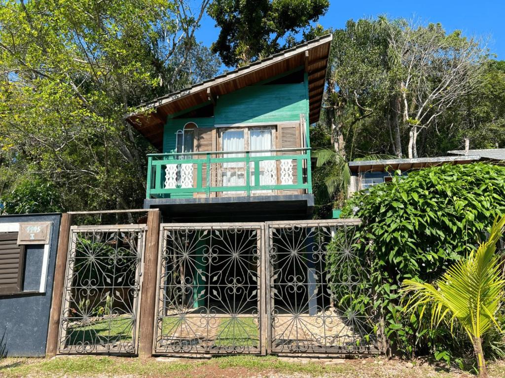 a house with a balcony and a gate at Casa Saíra in Bombinhas