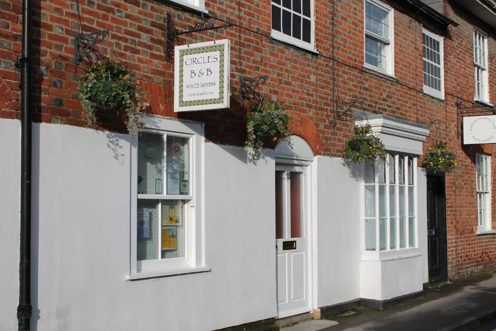 a white building with a sign on the side of it at Circles Guest House in Pewsey