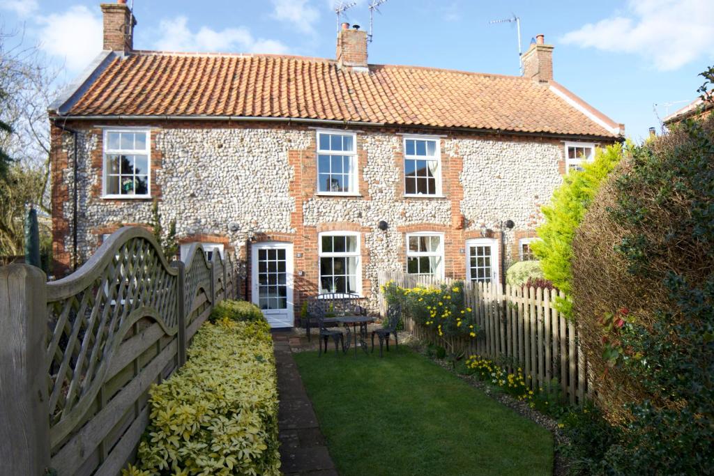 an old brick house with a fence in front of it at Norfolk Chapel Cottages in Docking
