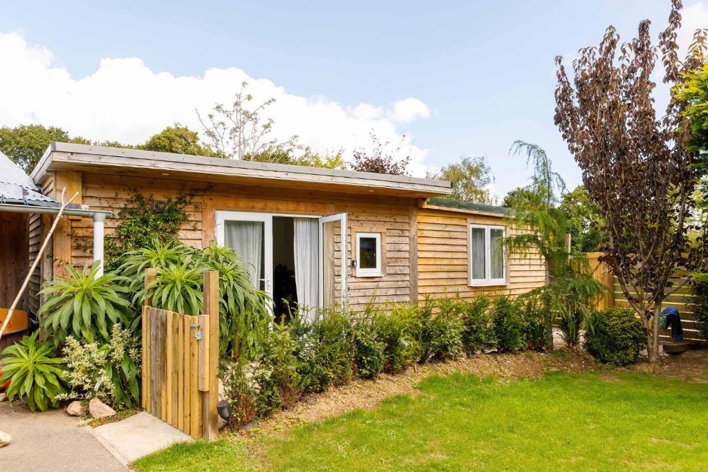 a small house with a fence in a yard at Cosy Cabin Retreat Close to Beaches in Birdham