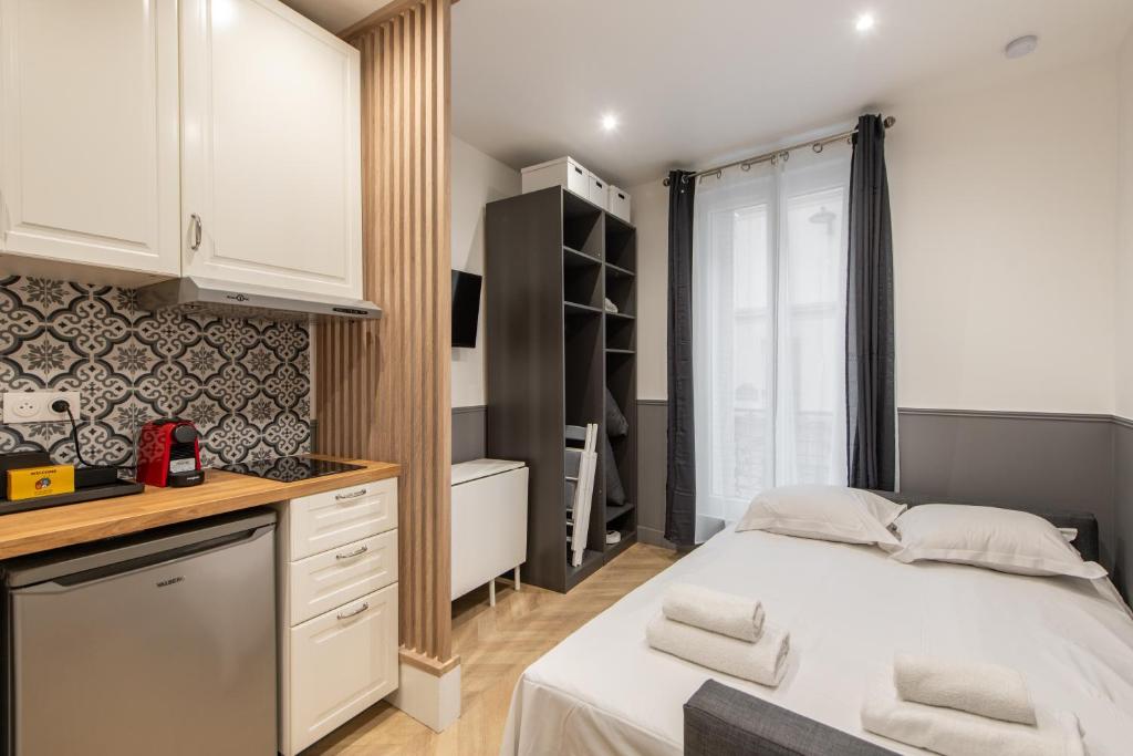 une petite chambre avec un lit et une cuisine dans l'établissement Raymond - Cosy studio proche Montparnasse, à Paris