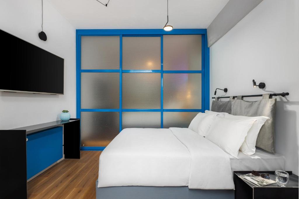 a bedroom with a large white bed and a tv at Fabrica PlayLoft in the City Center by BiNoBi! in Thessaloniki
