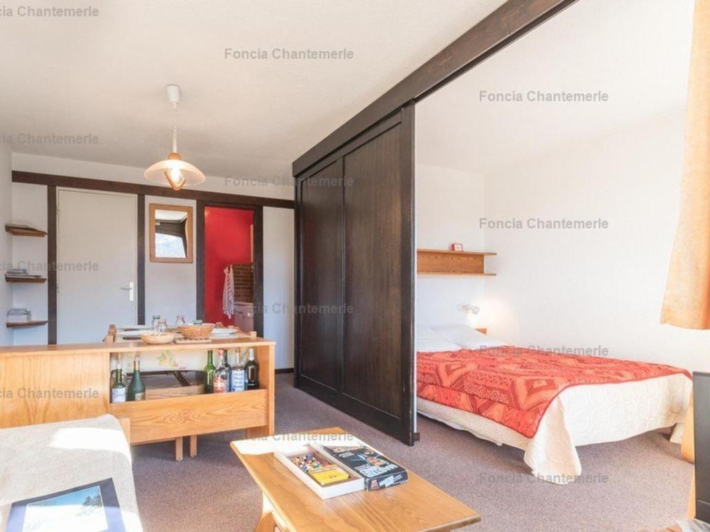 ein Schlafzimmer mit einem Bett und einem Tisch in einem Zimmer in der Unterkunft Charmant studio 4 pers à Serre-Chevalier avec balcon, TV, lave-vaisselle - Animaux non admis - FR-1-330E-43 in Serre Chevalier