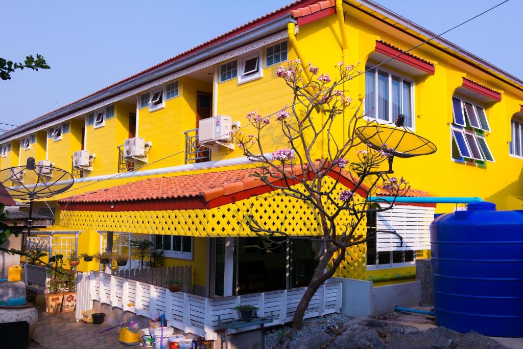 a yellow building with a tree in front of it at Rak Ban Kerd House in Ko Si Chang