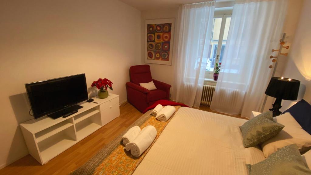 a living room with a television and a red chair at Hilda: Tranquillo appartamento in centro in Zürich