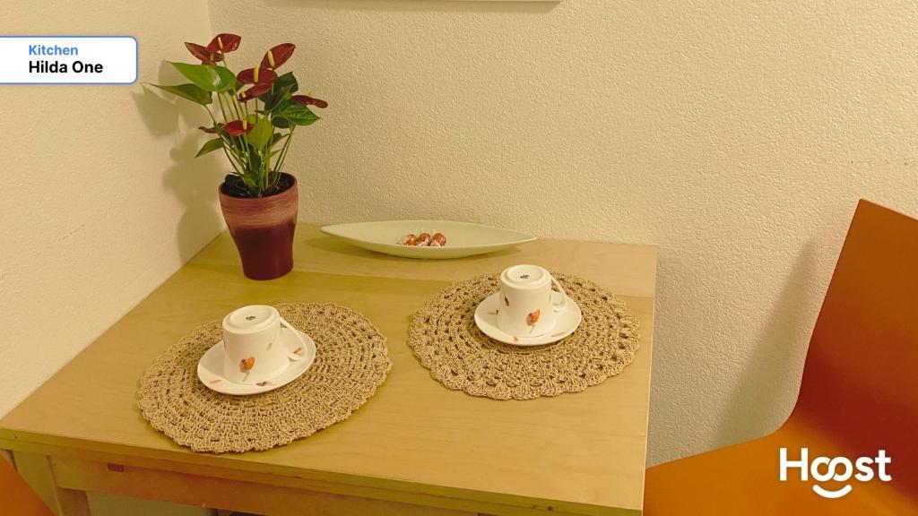two cups and saucers on a table with a vase at Hilda: Tranquillo appartamento in centro in Zürich