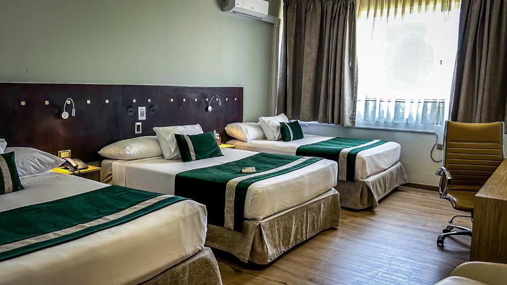 a hotel room with three beds and a window at Ecohotel Talca in Talca