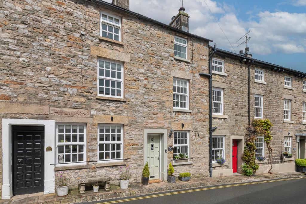 a brick building with white windows and red doors at Weavers Cottage Newly converted luxurious retreat in Kirkby Lonsdale