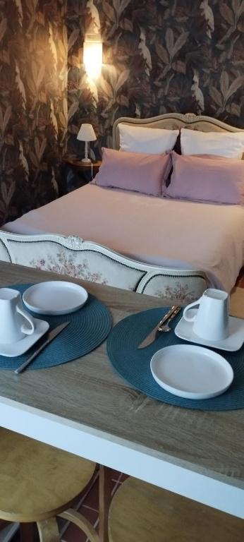une table avec des assiettes et des ustensiles sur un lit dans l'établissement Auprès du château 2, à Brézé
