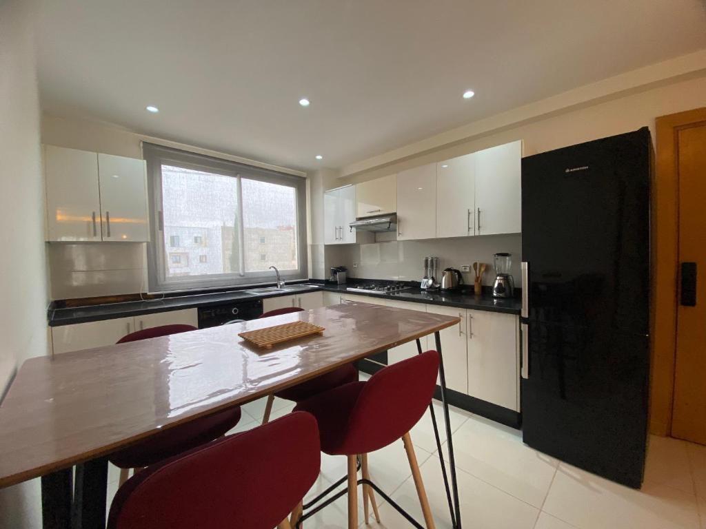 a kitchen with a wooden table and red chairs at Appartement Vue Mer piscine olympique in Aourir