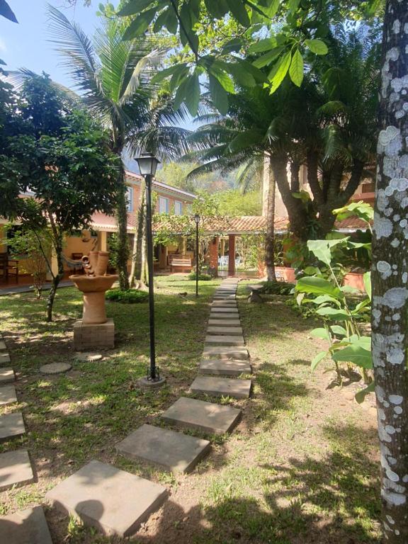a path in a garden with a street light and palm trees at Suítes Quintal de Lázaro 2 in Ubatuba