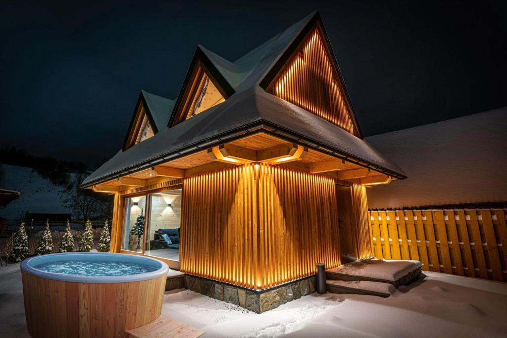 a building with a hot tub in the snow at Górska Baja Premium House in Witów