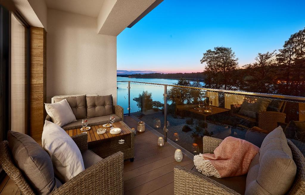 Un balcón con sofás y vista al agua. en Boszkowo Horizon Park Apartament 36 "Kwiecisty sen", en Boszkowo