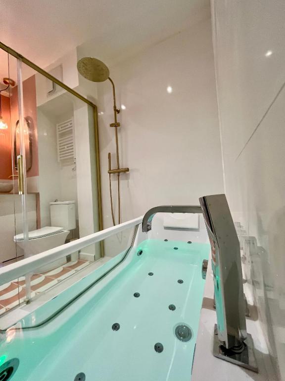 La salle de bains est pourvue d'une grande baignoire bleue. dans l'établissement Le Bellegarde - hypercentre et jacuzzi, à Toulouse