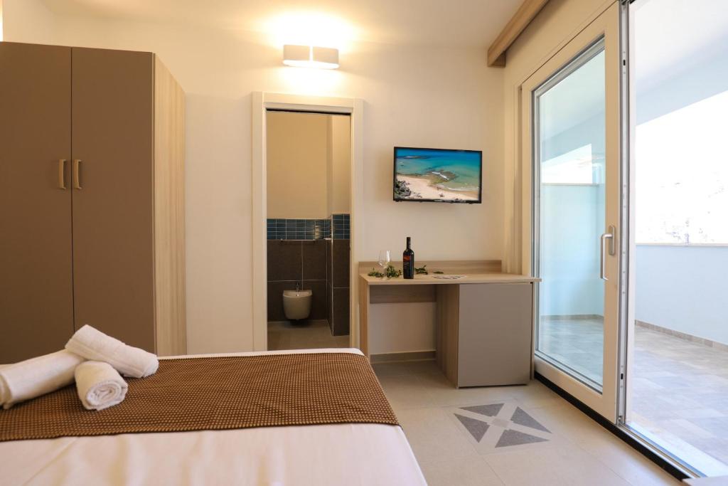 una camera con letto e scrivania e un bagno di The Square Castelsardo a Castelsardo