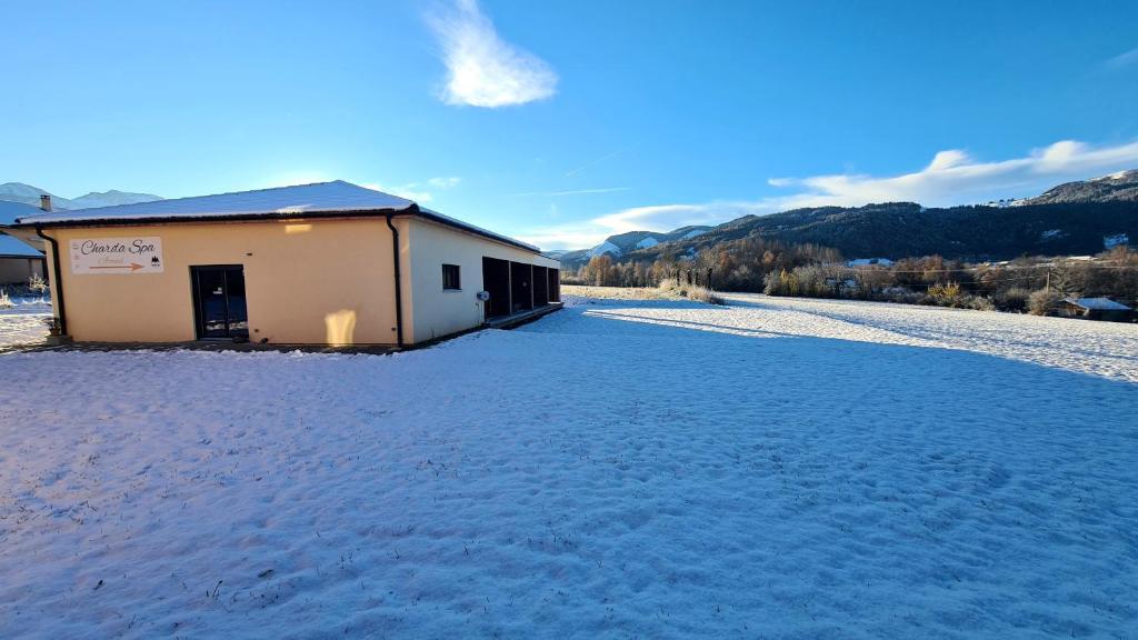 un champ couvert de neige avec un bâtiment en arrière-plan dans l'établissement Charda Spa, à Seyne