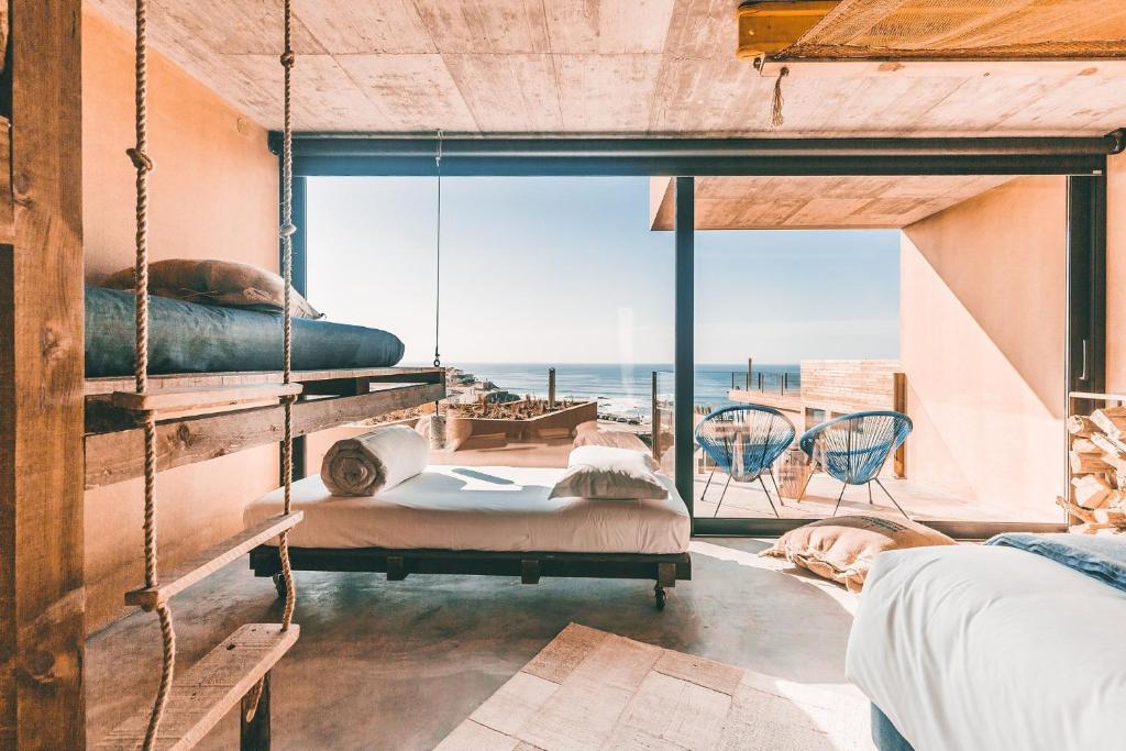a bedroom with two beds and a view of the ocean at Noah Surf House Portugal in Santa Cruz