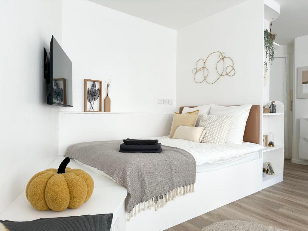 - une chambre blanche avec un lit et une citrouille sur un banc dans l'établissement Apt lumileux with sunshine, à Paris