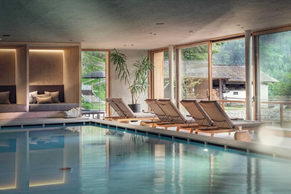 a room with a pool with chairs and windows at Naturhotel Saalerwirt in San Lorenzo di Sebato